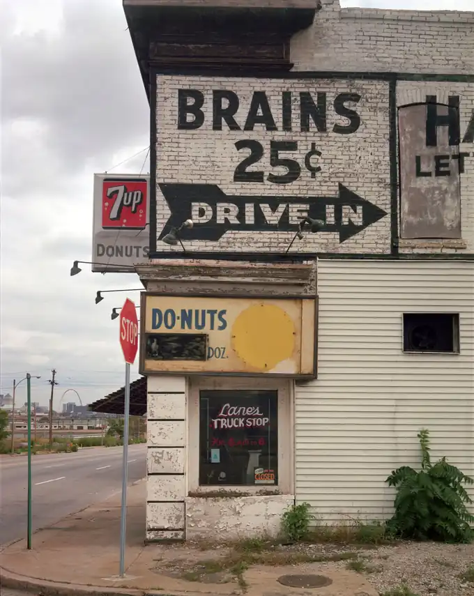 A weathered corner building displays Brains 25 cents and drive-in signs in St. Louis.