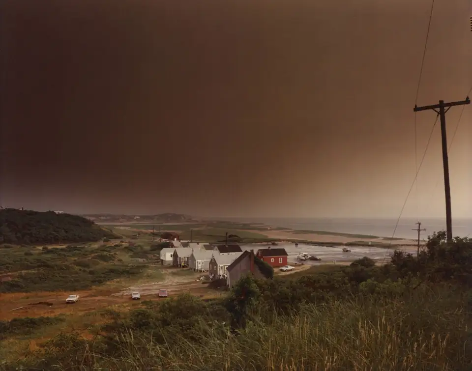 A dark storm sky hangs above cottages, dunes and the shoreline at Corn Hill Beach.
