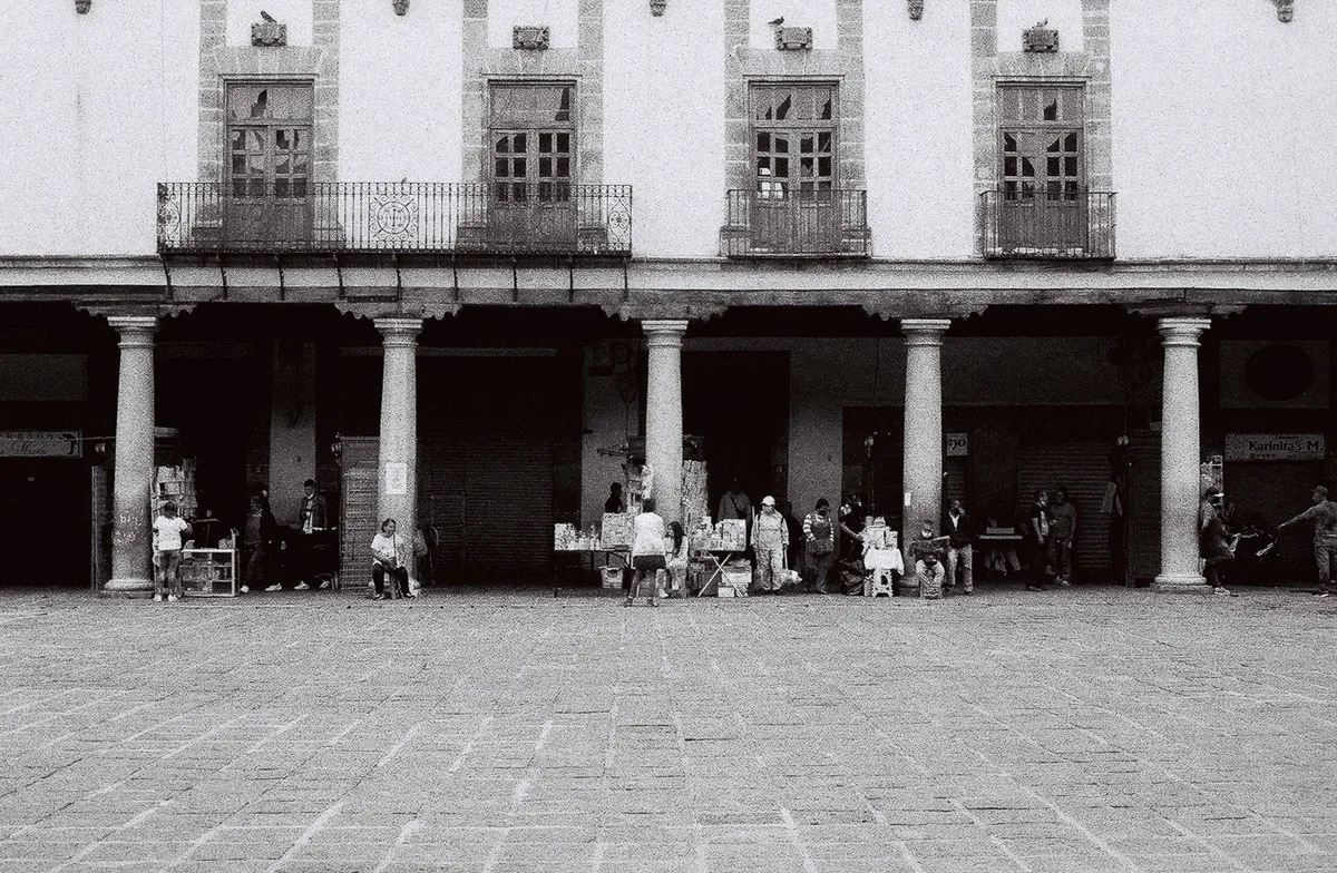 Black-and-white street scene on film by commercial film photographer Frederik Trovatten, showing vendors beneath a Mexico City colonnade.