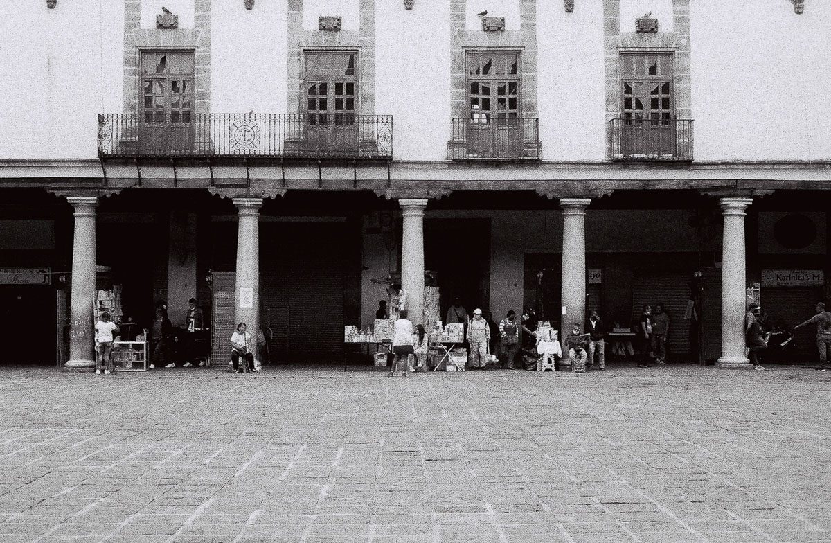 Black-and-white street scene on film by commercial film photographer Frederik Trovatten, showing vendors beneath a Mexico City colonnade.