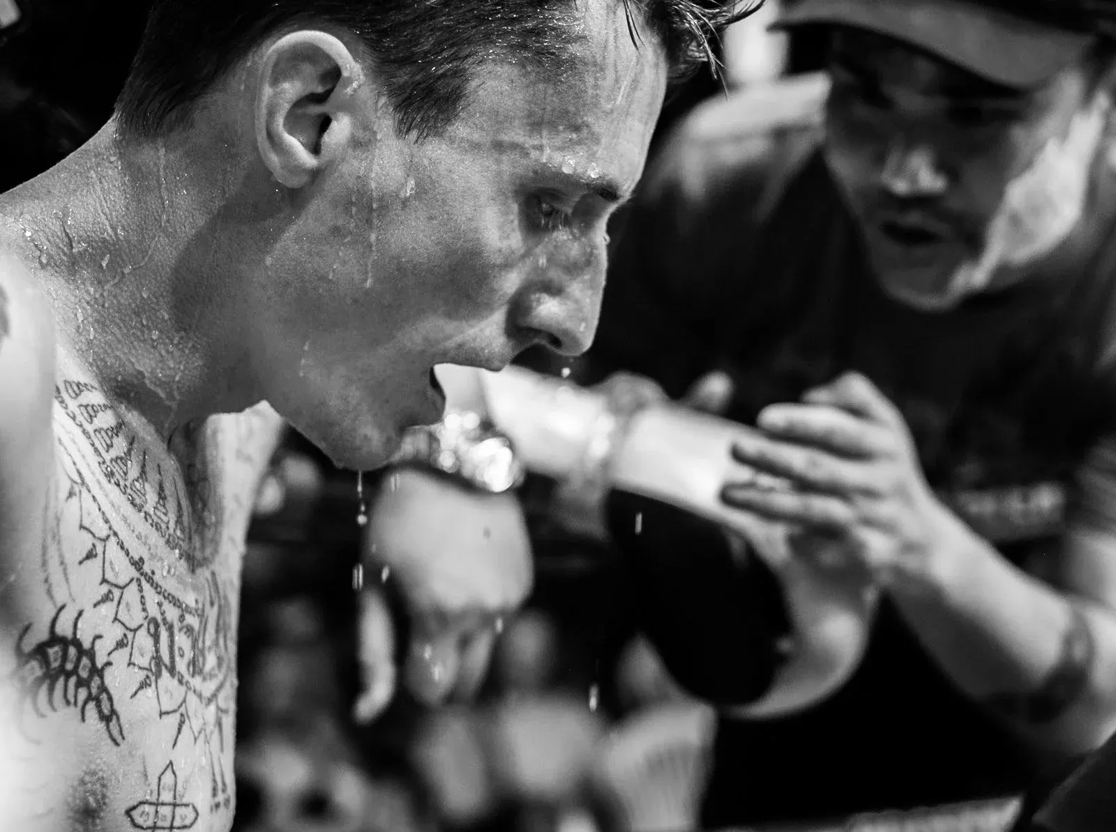 Sweating Muay Thai fighter listens to his corner between rounds