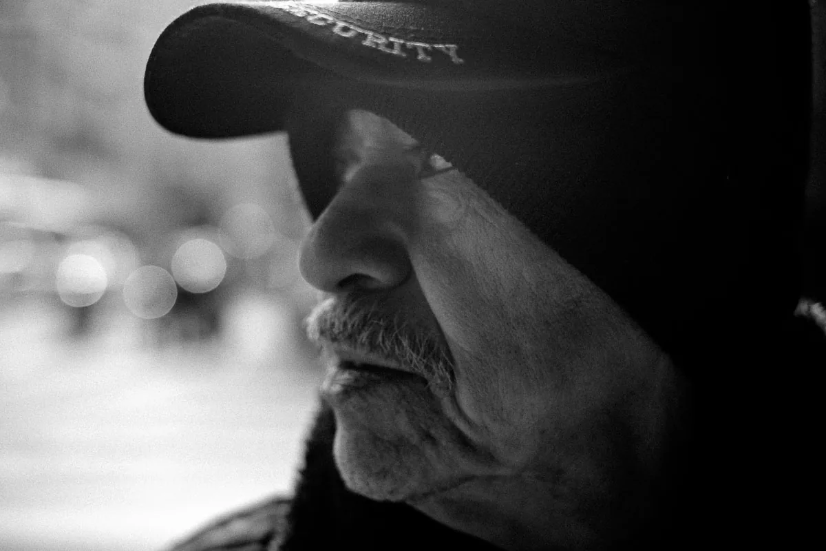 Close black-and-white NYC street portrait of a man in a cap