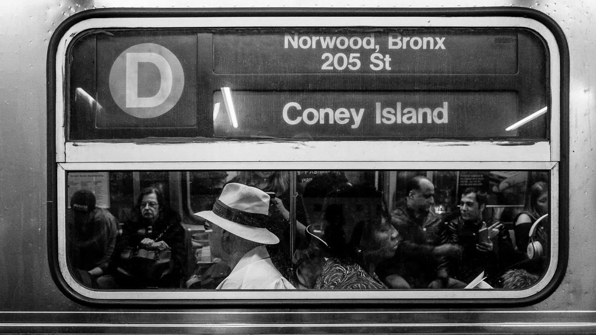 Black-and-white NYC subway photograph of passengers on the D train to Coney Island